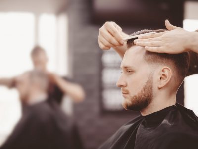 Barbershop banner. Man in barber chair, hairdresser styling his hair